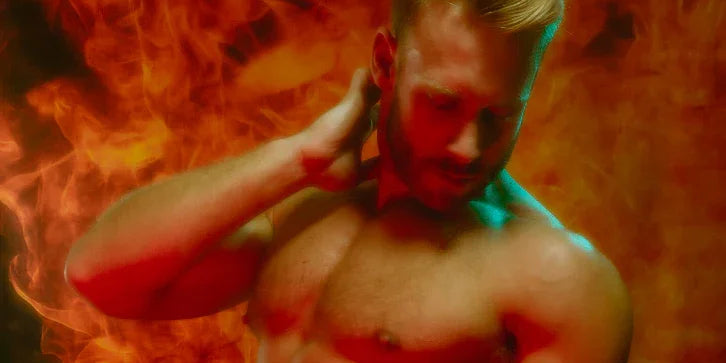 Shirtless muscular man posing against fiery orange background, highlighting athletic physique