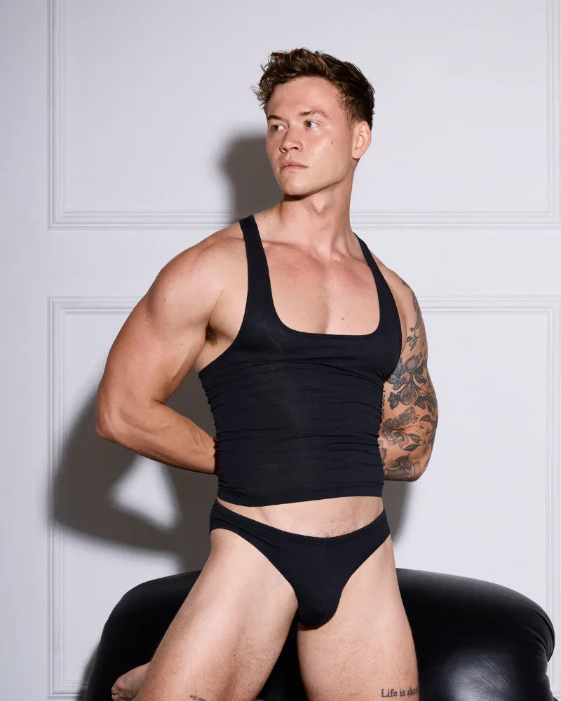 Muscular man in black tank top and low-rise briefs, showcasing athletic fit underwear for men