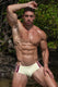 Muscular man in cream swim briefs with burgundy stripes, posing outdoors near water